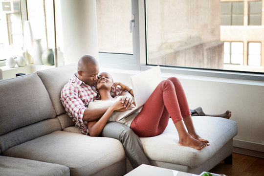 Happy couple at home relaxing using laptop together 