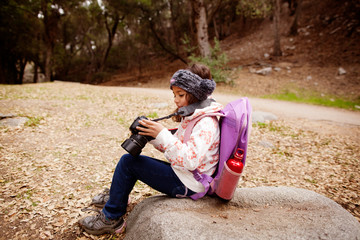 Girl (6-7) sitting on rock and looking at camera 