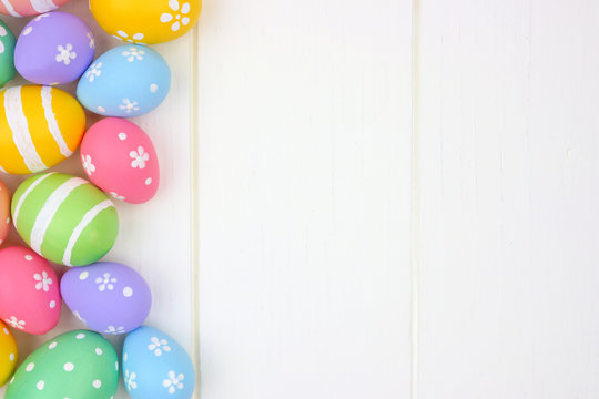 Colorful pastel Easter Egg side border against a white wood background. Top view with copy space.