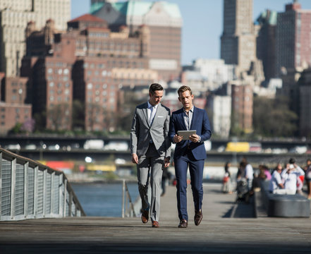 Businessmen walking talking and holding digital tablet 
