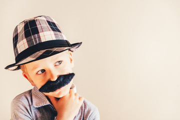 Funny child with fake mustache gesturing like an adult man, maturity and business concept.