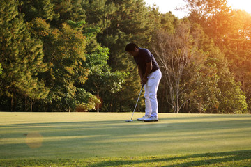 Golfer putting golf ball on the green golf