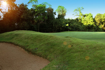The evening golf course has sunlight shining down at golf course in Thailand