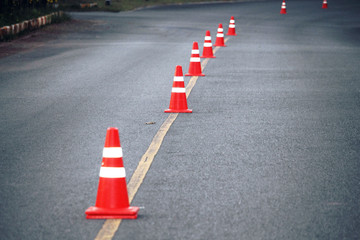 bright orange traffic cones standing in a row on dark asphalt