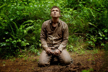 Man kneeling on rainforest path 