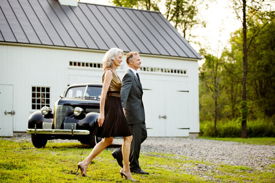 Glamorous mature couple walking by vintage car 
