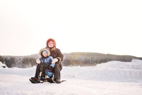 Mom and son (2-3) sitting on snow mobile 