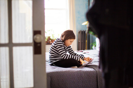 Girl (10-11) using digital tablet in her room 