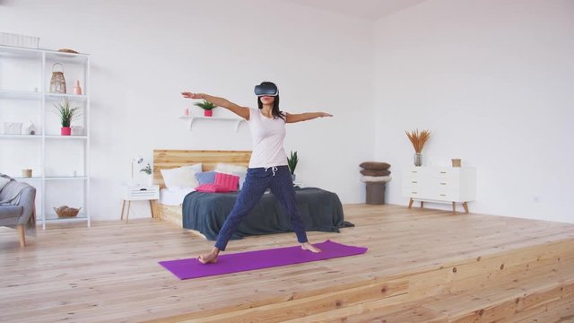Young female doing yoga in VR glasses at home, slow motion