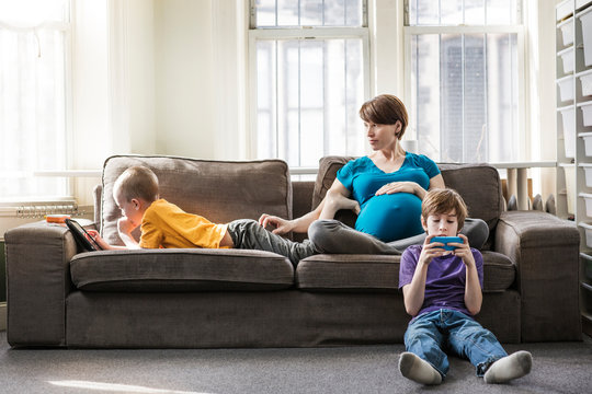 Pregnant woman with her children sitting at home