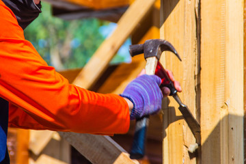 Carpenter is using chisel and hammer to groove vertical line. Close up hands of carpenter with chisel and hammer during grooving work.