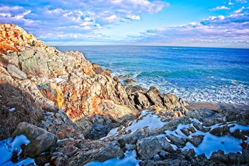 Snowy and rocky overlook of the ocean and coast during winter