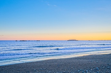View of the ocean and beach waves during sunset in the winter