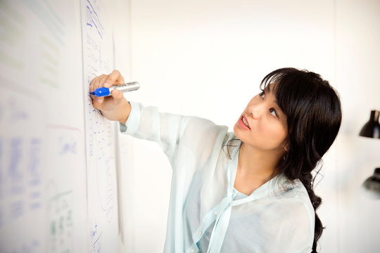 Young woman writing on white wall 