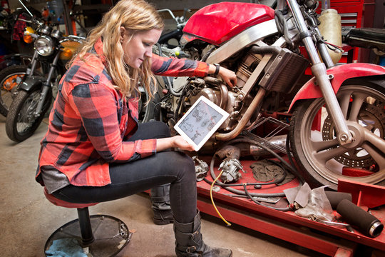 Female mechanic using digital tablet for repairing motorcycle 
