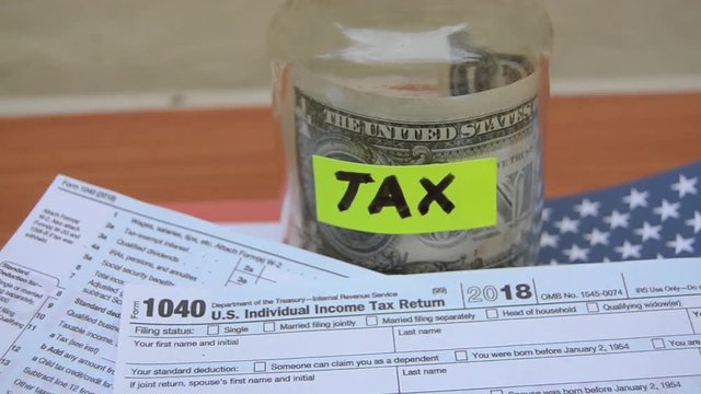 jar with tax label one dollar note and 1040 form moving on the wind