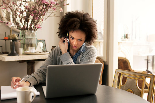 Woman at home using phone and laptop  