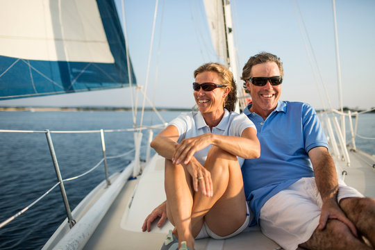 Married Couple Relaxing On Deck Of Private Yacht 