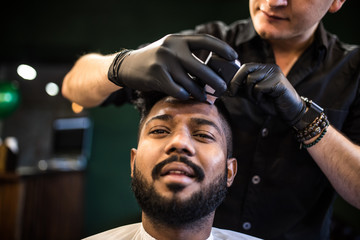 Close up of hairstylist trimming senior client hair in barber shop