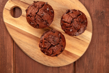 An overhead photo of chocolate chip muffins on a dark rustic wooden background