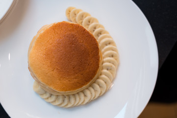Pancakes on a white plate with sliced bananas