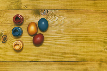 Painted Easter eggs  and colors for painting on wooden table.Toned photo.