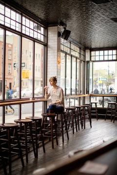 Young woman sitting by window in bar 