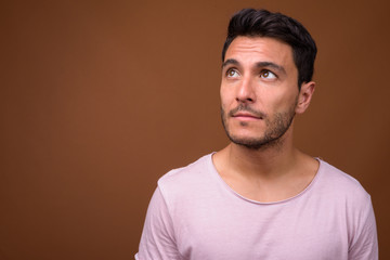 Young handsome Hispanic man against brown background