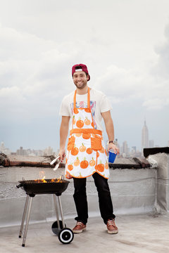 Young man in apron using grill 