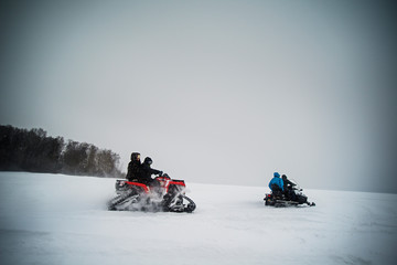 Family with children (8-9, 10-11) snowmobiling in winter