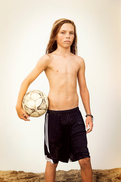 Portrait of boy (12-13) standing on beach and holding soccer ball 