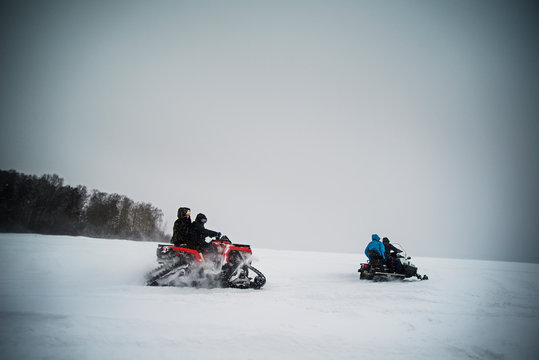 Family with children (8-9, 10-11) snowmobiling in winter 