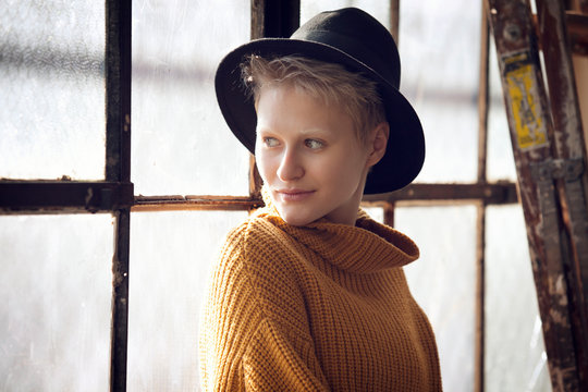 Portrait of young woman wearing hat in front of window 