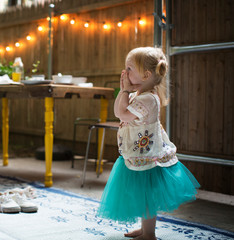 Side view of girl covering mouth standing indoors