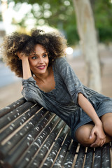 Young black woman with afro hairstyle smiling in urban background