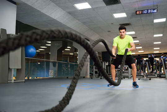 Man With Battle Ropes Exercise In The Fitness Gym.