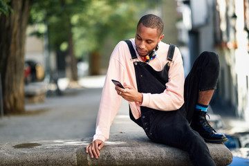 Obraz premium Young black man using smart phone outdoors