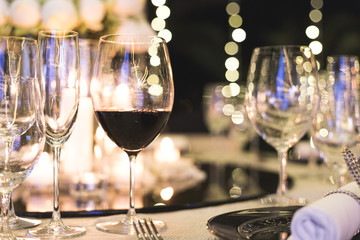 Wine glass cup on dinner table with one that have wine inside on blurred background