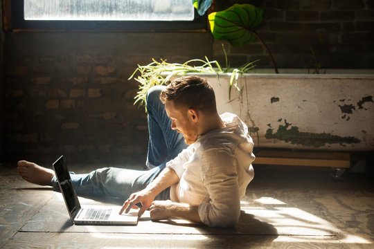 Young man using laptop on floor 