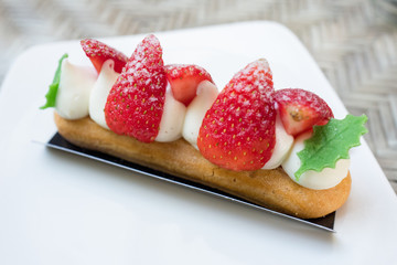 Strawberry dessert cake with sweet cream on white plate.