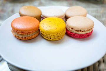 Colorful macaroon in variety taste on white round plate.