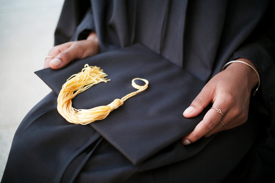 Mid-section of woman holding mortarboard 
