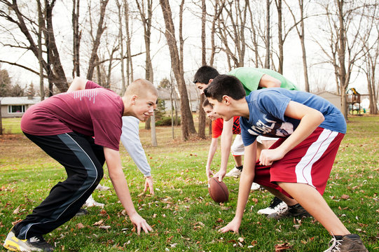 Teenage friends (12-13, 14-15 ) playing American football in back yard 