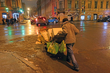 homeless man rolling cart down a street
