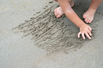 close up kid's foot and hand, play and learn at the beach.