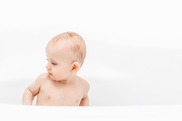 adorable child boy taking bath. Portrait of baby bathing in a bath with drops of water on the face. white background place for text
