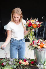Florist workplace. Woman arranging a bouquet with roses, chrysanthemum, carnation and other...
