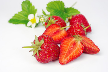 Ripe strawberries with leaves and flowers on white, close-up