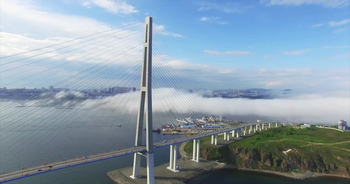 Beautiful aerial view of Russian bridge which connects the Russky Island and Vladivostok across the Eastern Bosphorus strait. Light morning fog is above the city