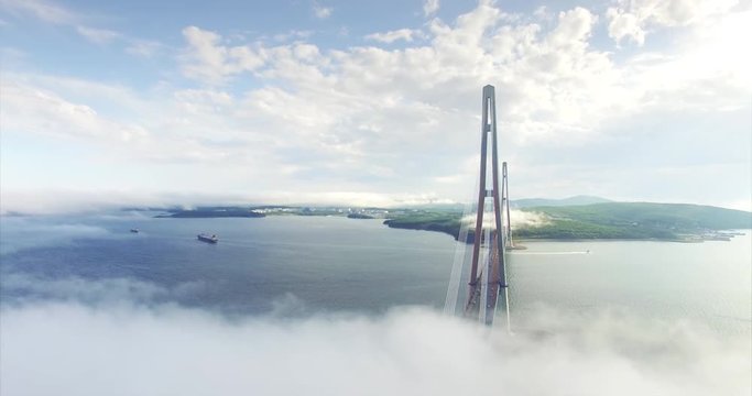 Aerial view of Russian bridge, longest cable-stayed bridge in the world. It connects Russky Island and Vladivostok across the Eastern Bosphorus strait. Light morning fog and clouds are around it